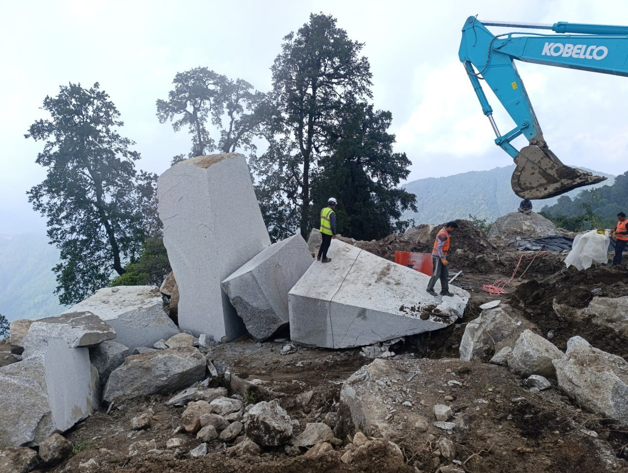 Large granite blocks, quarry workers and excavator at Kailash Granite Quarry in Kailash Rural Municipality, Makwanpur, Nepal.